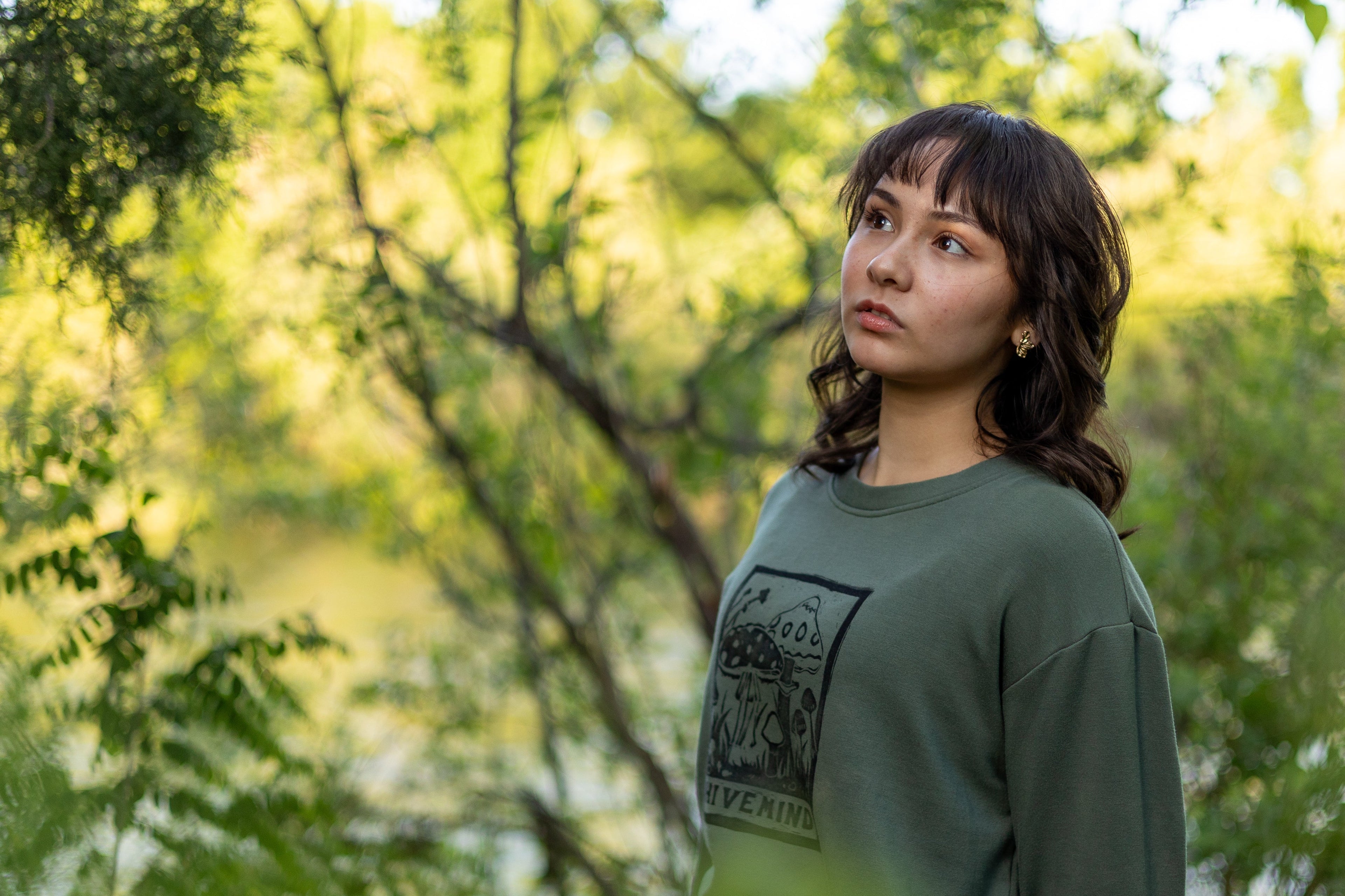 Woman in a green sweatshirt sitting among trees