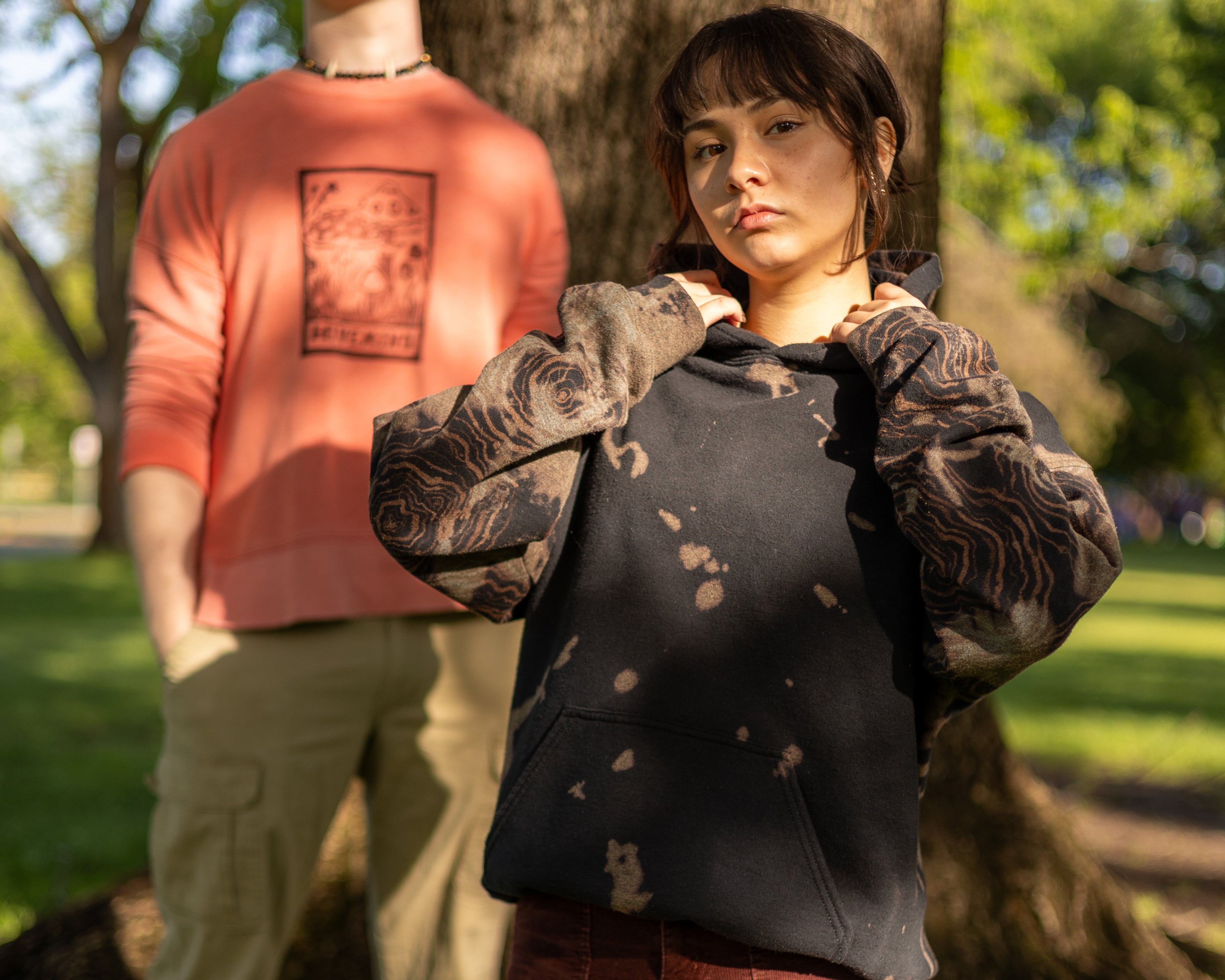 Two people standing in a park with trees and grass in the background